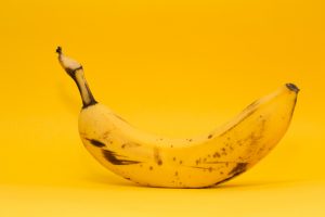 The is a picture of a scuffed up yellow banana on a banana yellow background.