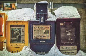 Yellow, blue, and black newspaper boxes in drifted snow in China. "Extree! Extree! Read all about it!"