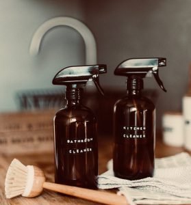 Two brown glass bottles with black plastic sprayers, one labeled "bathroom cleaner" and one labeled "kitchen cleaner." (Guess they couldn't come up with a cool name like "Sunshine Lemon Thyme"...)