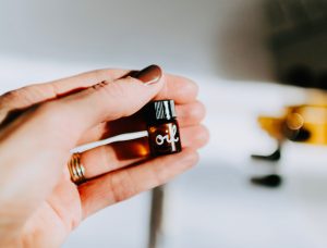 Woman's hand holding a teeny, tiny brown bottle labeled "oil".