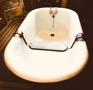 A divine deep clawfoot bathtub, with a shelf across it for resting your book, or your glass of wine